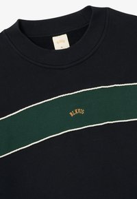 Must alusärgil on must värv, rohelise horisontaalse triibu ja valge äärisega. Brändi nimi "BLKVIS" on bordeeeritud oranžina triibu peale.