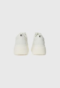 Hvit sneakers med glatt skinnutside, rund tå og tykk gummisåle. Har detaljer med svart logo på hælen.