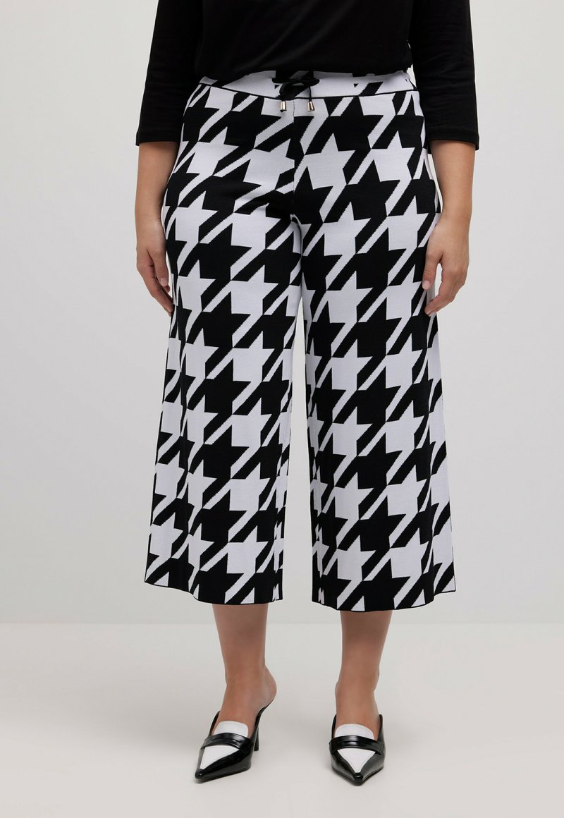 Zwart-witte houndstooth-gepatroneerde culottes met een elastische tailleband, voorzien van een trekkoord en metalen accenten. Korte wijde pasvorm.