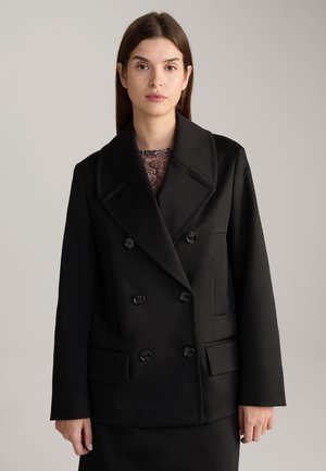 Cappotto doppiopetto nero con grandi rever, tessuto testurizzato, quattro bottoni e due tasche frontali, che offre una silhouette su misura.