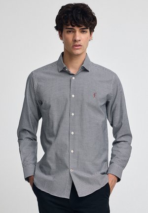 Zwart-wit geruit overhemd met knopen, kraag, lange mouwen en een klein logo op de borst; gladde stoftextuur.