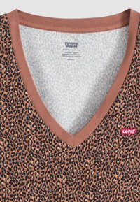 Levi's v-hals t-skjorte med et leopardmønster i brunt, svart og beige. Har en kontrastfarge i brun på halslinningen og et merke på siden.