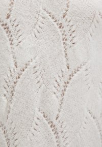 Knit sweater in soft white yarn featuring a textured leaf pattern. Material shows slight fuzziness with open stitches enhancing design depth.
