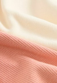 Stickad tyg med tre horisontella ränder: mjuk krämfärg, ljusbeige och rosaröd, med en subtil ribbad struktur och slät yta.