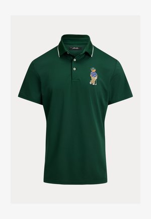 Polo verde scuro con colletto bordato di bianco e orso ricamato in abbigliamento da golf che tiene una mazza sul lato sinistro del petto.