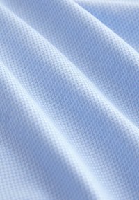 Ljusblått, texturerat tyg med ett vävt mönster som visar fina, korsande diagonala linjer för extra djup och detaljrikedom.