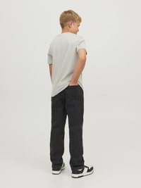 Grå t-shirt med kort ärm i kombination med svarta jeans. Svartvita sneakers fulländar outfiten. Enkel och avslappnad stil sett från baksidan.