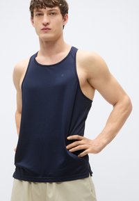 Αμάνικο αθλητικό τοπ σε ναυτικό μπλε χρώμα με ριμπ υφή, στρογγυλή λαιμόκοψη και μικρό λογότυπο στην αριστερή πλευρά. Εφαρμοστή σχεδίαση.