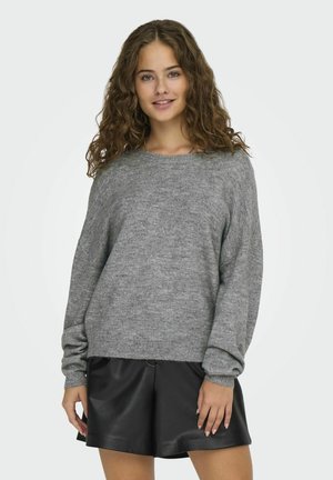Grijze gebreide trui met een ronde hals en verlaagde schouders, gecombineerd met zwarte neplederen shorts. Zachte textuur, comfortabele pasvorm.