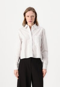 Camicia bianca a righe con bottoni, caratterizzata da maniche lunghe, colletto a punta e un design corto con una finitura texturizzata.