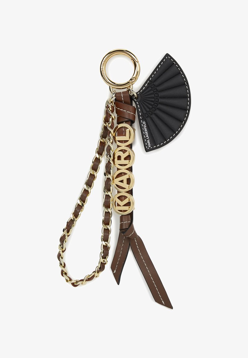 Pruun nahast võtmehoidja kuldsetest elementidest, millel on must fännikujuline ripats ja "KARL" logo kuldsetes tähtedes. Kett ja põskedetailid.