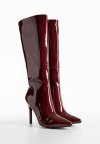 Bottes à talons en cuir verni bordeaux hauteur genou, avec un bout pointu et une finition brillante, présentant un design élégant et un talon aiguille fin.