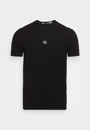 Schwarzes T-Shirt mit kurzen Ärmeln und Rundhalsausschnitt mit kleinem weißen "CK" Calvin Klein Jeans-Logo mittig auf der Brust.