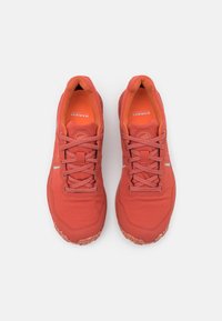 Röda trail-löparskor med en strukturerad ovandel, snörning och gummiyttersula; har reflekterande detaljer och vadderad insida.