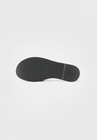 Svart såle med en glatt overflate, rund form, og et mønster for bedre grep, med en sentral horisontal stripe for støtte.