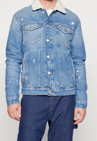 Ljusblå jeansjacka med krage i fårskinn, två bröstfickor, slitningseffekter och knappstängning framtill samt vid ärmslut.