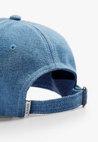 Denimkappe mit runder Krone und gebogenem Schirm. Blaue Farbe mit sichtbaren Nähten und einem verstellbaren Metallverschluss auf der Rückseite.