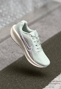 Lys grønne løbesko med en struktureret mesh-overdel, hvide accenter og en støttende sål. Har et swoosh-logo og struktureret detaljering.