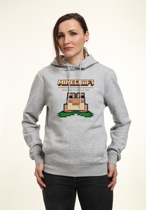 Szara bluza z kapturem z grafiką Minecraftu przedstawiającą pikselowy dom na zielonej trawie. Sznurki i ściągacze na mankietach dopełniają design.