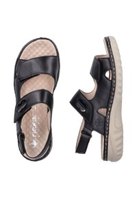 Sandales en cuir noir avec une semelle intérieure beige texturée, deux sangles ajustables, des découpes et une semelle extérieure en caoutchouc beige.