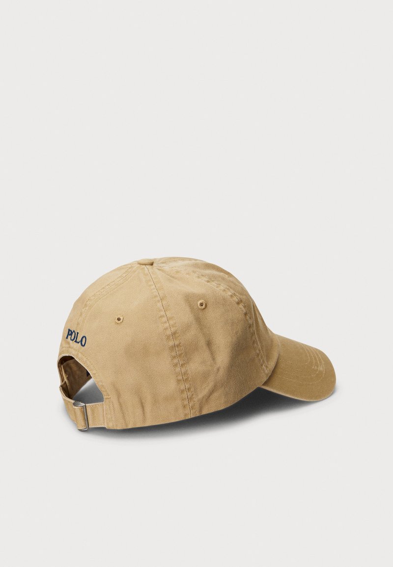 Lichtbruine verstelbare baseballcap met "POLO" in het blauw geborduurd op de achterkant, afgebeeld tegen een effen witte achtergrond.