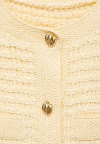 Żółty dziergany kardigan z fakturowanym wzorem, ozdobiony złotym skręconym guzikiem i małą kieszonką z przodu. Miękka, fakturowana tkanina.