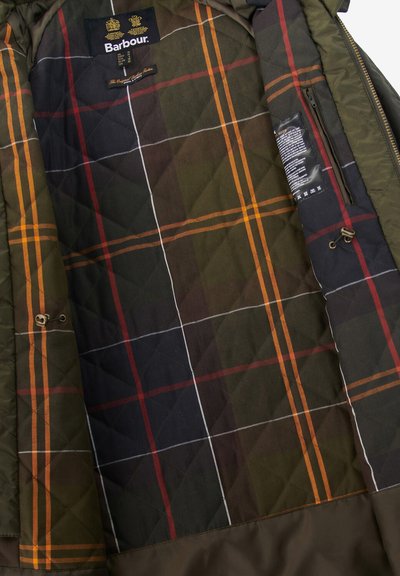 Вътрешността на якето Barbour има зелена и кафява каре с акценти в оранжево и червено, капковидна текстура и здрав цип.