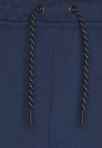 Cintura de color azul marino con cordón negro que presenta rayas blancas, hecha de una tela suave y elástica, con detalles de costura texturizada.