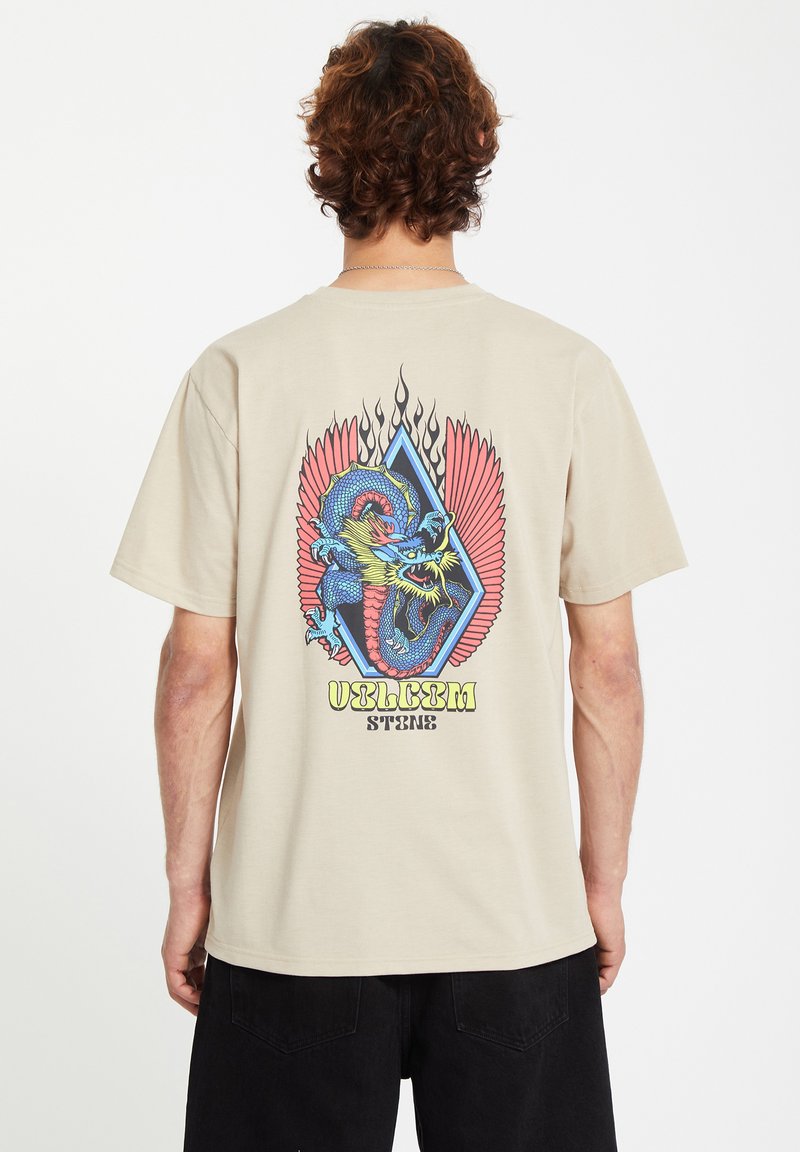 Beige bomulds t-shirt med et farverigt dragegrafik med røde vinger og blå detaljer, placeret inden i en diamantform med et flammedesign.