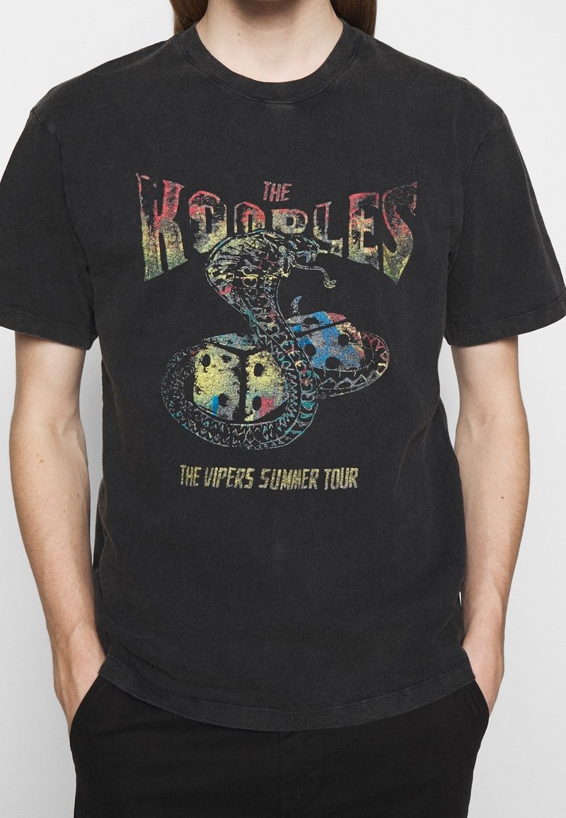 Camiseta de algodón negra con un gráfico colorido de una serpiente con dados, y el texto "THE KOOBLES" arriba y "THE VIPERS SUMMER TOUR" abajo.