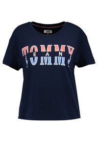 Námořnická modrá bavlněná tričko s krátkým rukávem a kulatým výstřihem. Na přední straně se nachází výrazná grafika "TOMMY JEANS" v červené a bílé barvě.