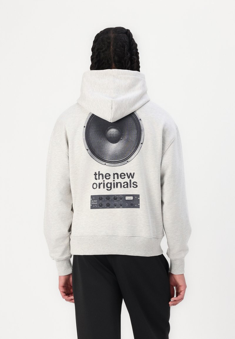 Grå hettegenser med hette, med et stort svart høyttaler grafikk og teksten "de nye originalene" på baksiden. Stoffet er mykt og strukturert.
