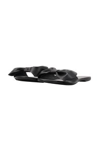 Zwarte slide-sandalen met een soepele leren bovenkant, oversized strikaccenten, open zijkanten en een platte zool. Gewatteerde binnenzool voor comfort.
