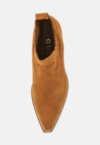 Botine din suede maro, cu vârful ascuțit, panouri elastice pe laturile laterale și cusături decorative pe mijlocul tălpii. Logo-ul mărcii vizibil în interior.