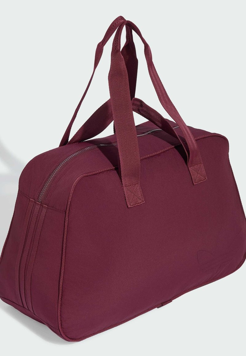 Borsa sportiva in tessuto morbido color marrone scuro con doppia tracolla e chiusura superiore a cerniera, ideale per viaggi o palestra.