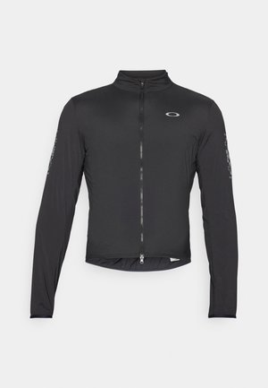 Juodas ilgomis rankovėmis dviratininkų švarkas su aukštu apykakle, visiškai užtrauktuku priekyje ir elastingais rankogaliais. Yra logotipas ant krūtinės ir spausdinti akcentai ant rankovių.