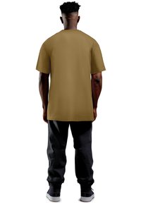 T-shirt a maniche corte oversize in tessuto verde oliva, con orlo dritto, abbinata a pantaloni neri larghi e sneaker nere.