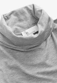 Grauer Rollkragenpullover aus weichem, strukturiertem Stoff mit umgeschlagenem Kragen und sichtbarem Pflegeetikett. Einfaches Design, leicht lässige Passform.