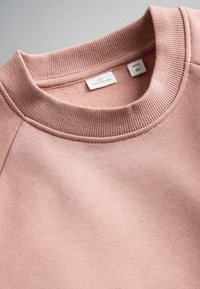 Ružová mikina s okrúhlym výstrihom pre deti vo veku 6 rokov, zobrazuje rebrovaný golier a štruktúru látky, s prišitými štítkami veľkosti a pôvodu.