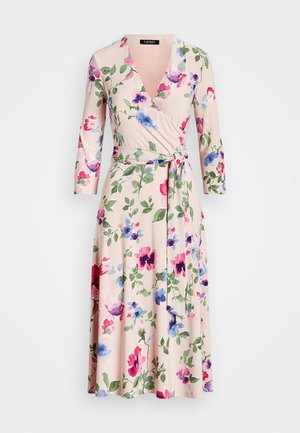 Robe portefeuille florale en tissu doux rose pâle. Présente des fleurs vibrantes violettes, roses et bleues avec des feuilles vertes. Manches mi-longues et ceinture à nouer.