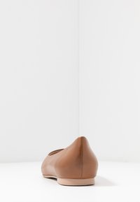 Hnědá kožená plochá bota s kulatou špičkou a mírným podpatkem. Hladký povrch a minimalistický design. Pevná podrážka, bez viditelného hardwaru.