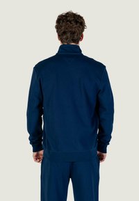 Felpa con zip color blu navy realizzata in tessuto morbido, con collo alto, maniche lunghe e orlo a costine. Design semplice senza motivi.