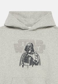 Sudadera gris con capucha amplia, con un gráfico de un personaje con casco y el texto "STAR WARS" en tonos más oscuros detrás.