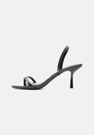 Fekete, magas sarkú szandál vékony lábujj- és boka pántokkal, fényes felülettel és vékony tűsarkúval.