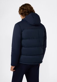 Giacca a puffo blu navy con cappuccio, dotata di design trapuntato, texture liscia e polsini elasticizzati. La vista posteriore non mostra loghi visibili.