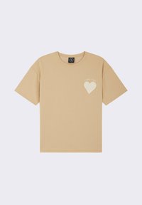 Camiseta de algodón beige de manga corta, con cuello redondo y un diseño de corazón texturizado en el lado izquierdo del pecho que presenta el texto "Project & Polly."