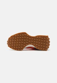 Schuhsohle mit einer strukturierten, braunen Gummifläche, die runde Griffe, eine geschwungene Form und einen weißen Rand aufweist.
