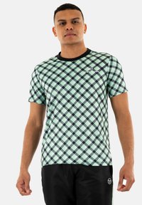 T-shirt a maniche corte, verde menta a quadratini con un motivo geometrico, caratterizzato da un colletto nero e un logo sul petto. Il tessuto appare liscio.