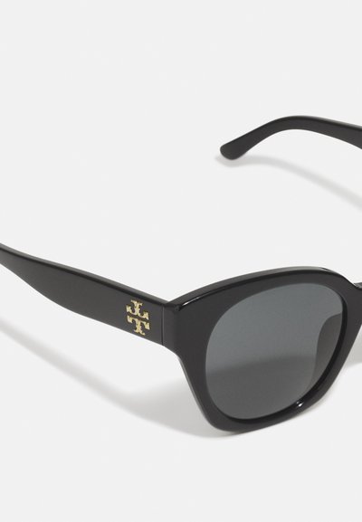 Óculos de sol de plástico preto com lentes escuras, apresentando um detalhe do logotipo dourado na lateral e um design de armação arrojado e angular.