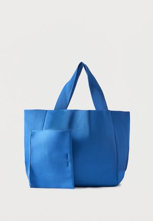 Sac cabas en tissu côtelé bleu avec deux poignées et une pochette amovible assortie, posé sur un fond blanc uni.